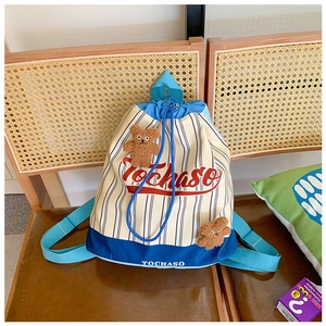 Detail of striped drawstring backpack with cute brown bear charms and blue straps