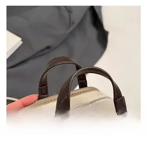 Détail du sac à main enfant en cuir crème avec poignée marron et boucles métalliques