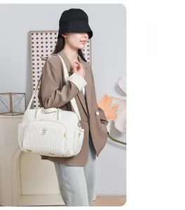 Sac à langer matelassé blanc avec bandoulière réglable et détails dorés à l'intérieur