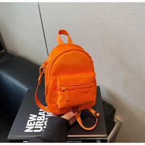 Detail of bright orange mini nylon shoulder bag with adjustable straps and zipper pocket