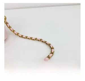 Détail de la bandoulière en cuir rose tressé avec chaîne dorée sur un sac seau enfant