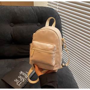 Detail of beige nylon mini backpack showing smooth zippers and adjustable woven strap