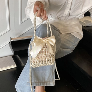 Elegant pearl beaded mini handbag featuring a large satin bow and woven pearl chain strap