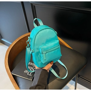 Close-up of mint green nylon mini crossbody bag with double zipper pockets on a chair