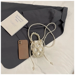 Dettaglio della mini borsa a secchiello in perle con coulisse in raso e catena