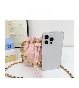 Mini sac seau matelassé rose posé à côté d'un smartphone pour montrer sa petite taille