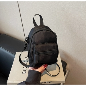 Detail of mini black nylon shoulder bag showing zipper pocket and durable hand strap