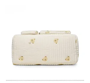 Detailed bottom view of a quilted cream diaper bag with cute yellow bear print patterns