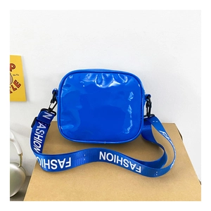 Close-up of bright blue shiny cross-body bag with wide white-lettered fashion strap