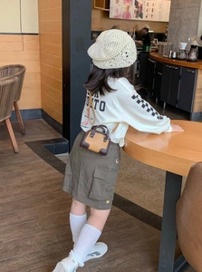 Sac bandoulière tendance pour filles en marron et beige contrasté, porté dans un café