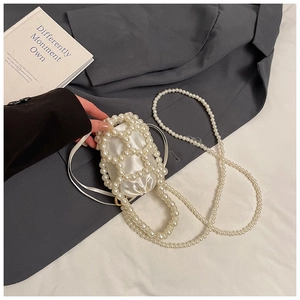 Dettaglio della mini borsa a secchiello in perle con fodera in raso bianco e tracolla