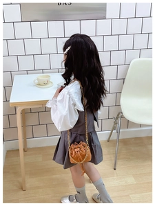 Détail du sac seau matelassé caramel avec bandoulière chaîne dorée et cordon de serrage