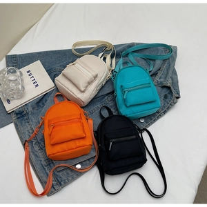 Mini nylon crossbody bags in ivory, blue, orange, and black on denim background