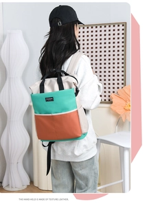 Detail of color-block diaper bag with texture leather handle and fashion brand label