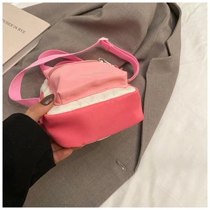 Detail of small canvas crossbody bag with pink color blocking and adjustable strap