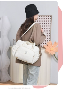 Détail du sac à langer matelassé blanc avec motif d'ours et poignées en cuir texturé