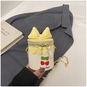 Détail du mini sac seau avec imprimé cerise, nœud jaune et bandoulière dorée