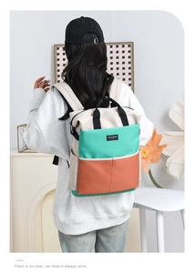 Detail view of stylish color-block diaper bag in beige, mint, and orange on model