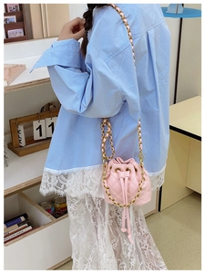 Détail du mini sac seau matelassé rose avec bandoulière chaîne dorée et cordon de serrage