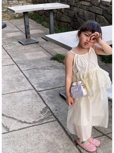 Detail of baby girl tiered dress paired with a purple sequined bow crossbody bag