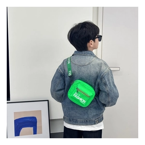 Child wearing fluorescent green crossbody bag with adjustable lettered strap in minimalist room