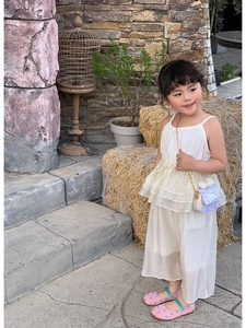 Detail of purple sequin mini shoulder bag with white bow and gold chain on child model