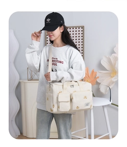 Detail of quilted beige baby bag with bear pattern worn as a crossbody by a model