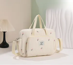 Détail du sac à langer matelassé crème avec broderie florale et bandoulière réglable
