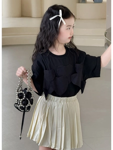 Dettaglio di bambina con t-shirt nera a cuore e gonna a pieghe crema con borsa di perline
