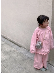 Detail of a shiny silver sequined kids handbag with a bow on pink clothing