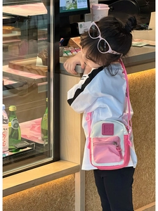 Close-up of pink and white kids crossbody bag with adjustable strap and square logo