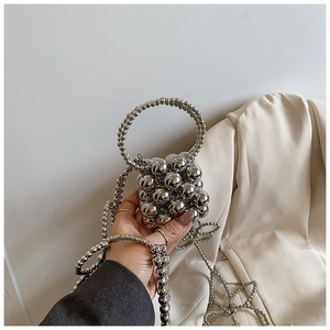 Dettaglio ravvicinato di una mini borsa a secchiello in perle argentate con catena in metallo