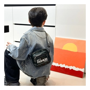 Detail of kids black patent leather crossbody bag with logo strap worn by child model