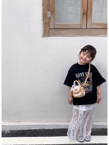 Détail d'une tenue d'été pour fille avec t-shirt noir à motif et jupe en dentelle blanche