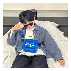 Detail of the blue patent leather kids chest bag with lettered fabric shoulder strap