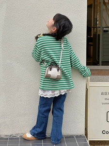 Fille en pull rayé vert et jean avec sac à main élégant beige en contraste
