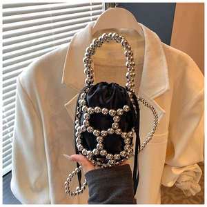Dettaglio di una mini borsa a secchiello con perle in metallo argento e coulisse