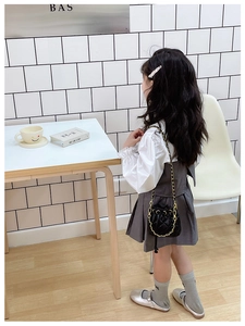 Détail du sac seau matelassé noir pour enfant avec bandoulière chaîne dorée sur mannequin