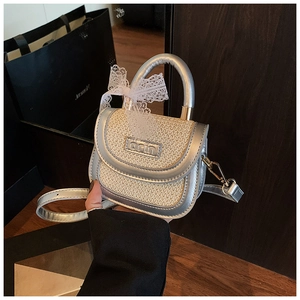Détail d'un sac en paille pour filles avec bordure métallique argentée et nœud en dentelle
