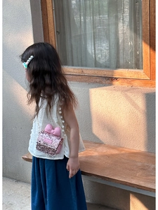 Pink sequin crossbody bag for kids with a soft bow detail and chain strap shown on a model