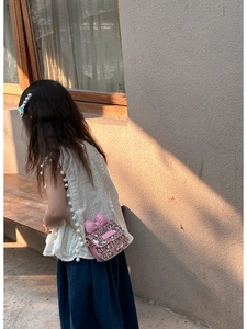 Detail of pink sequin crossbody bag for girls with leather bow and golden chain strap