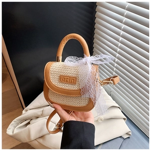 Détail du sac en paille pour enfants avec poignée en cuir brun et nœud en dentelle blanche
