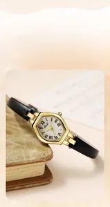 Close-up of rose gold tonneau watch with Roman numeral dial on a leather notebook