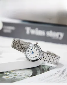 Close-up of silver steel watch with roman numerals, blue hands and wavy textured dial