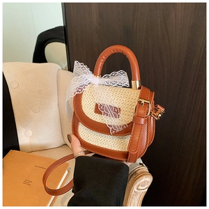Détail d'un mini sac en paille avec bordure en cuir caramel et nœud en dentelle blanche