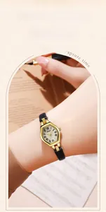 Close-up of a women's vintage tonneau gold watch with Roman numerals and black leather strap