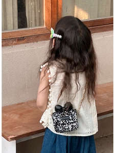 Close-up of child's black sequin crossbody bag with cute leather bow and gold chain strap