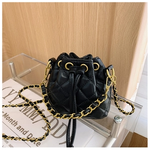 Détail d'un sac seau matelassé noir avec œillets dorés et bandoulière en chaîne