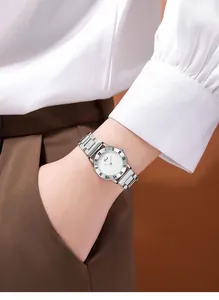Détail d'une montre en acier argenté avec cadran blanc à chiffres romains au poignet