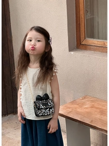 Close-up of girls black sequin mini shoulder bag with bow and gold chain strap